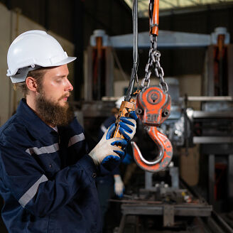 Two technicians inspecting and testing the operation of lifting cranes in heavy industrial plants.