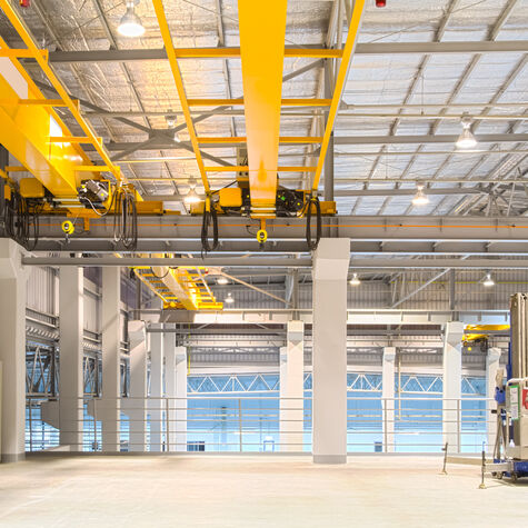 Concrete floor inside factory or warehouse building with empty space for industry background. Overhead crane or bridge crane include hoist lifting for transportation, manufacturing, and production.